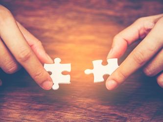 Person putting two jigsaw pieces together